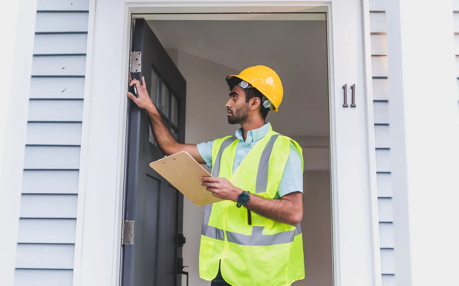 Building professional inspecting the exterior of a house with a clipboard